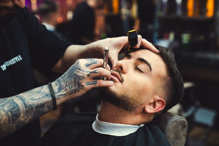 Un barbiere rifinisce la barba di un cliente